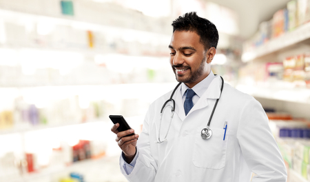 smiling indian male doctor with smartphoneの写真素材