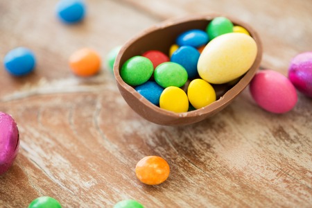 chocolate easter egg and candy drops on tableの写真素材