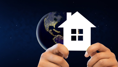 hands holding white house over earth in spaceの写真素材