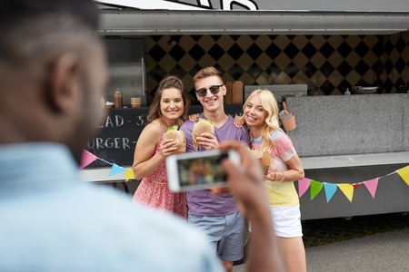 man taking picture of friends eating at food truck