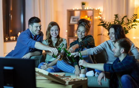 friends with drinks and pizza watching tv at homeの写真素材