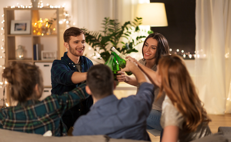 friends clinking drinks at home in eveningの写真素材