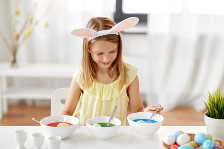 girl coloring easter eggs by liquid dye at homeの写真素材