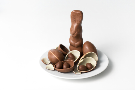 chocolate bunny, eggs and candies on white plateの写真素材