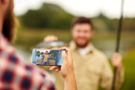 friend photographing fisherman by smartphoneの写真素材