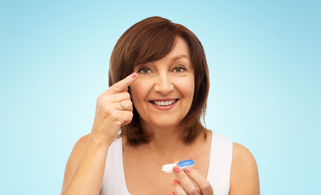 happy senior woman applying contact lensesの写真素材