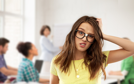 confused teenage student girl in glasses at schoolの写真素材