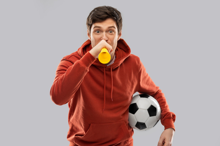 football fan with soccer ball blowing hornの写真素材