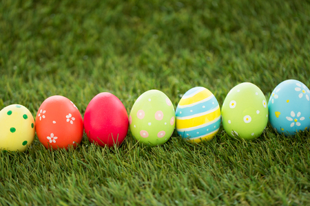 row of colored easter eggs on artificial grass