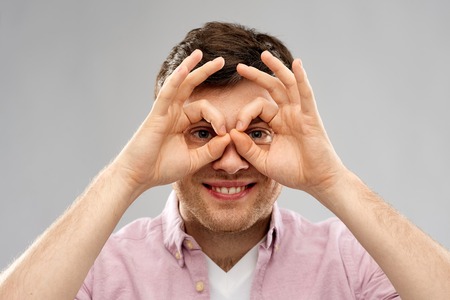 young man looking through finger glasses