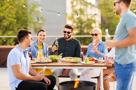 happy friends having bbq party on rooftopの写真素材