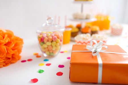 birthday present in orange wrap on table at partyの写真素材