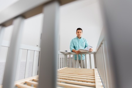 father with manual assembling baby bed at homeの写真素材