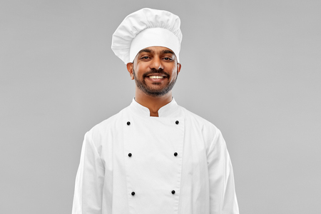 cooking, profession and people concept - happy male indian chef in toque over grey backgroundの写真素材
