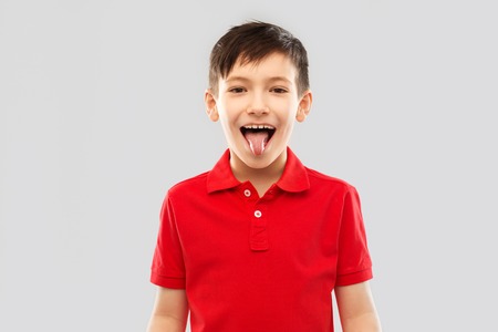 boy in red polo t-shirt showing his tongueの写真素材