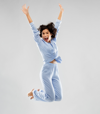 happy woman in blue pajama jumping highの写真素材