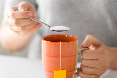 close up of woman adding sugar to cup of teaの写真素材