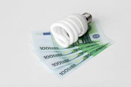 close up of energy saving lightbulb and euro moneyの写真素材