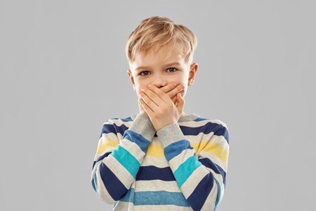 Shocked little boy closing his mouth by handsの写真素材