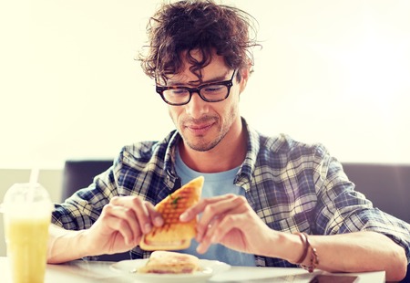 happy man eating sandwich at cafe for lunchの写真素材