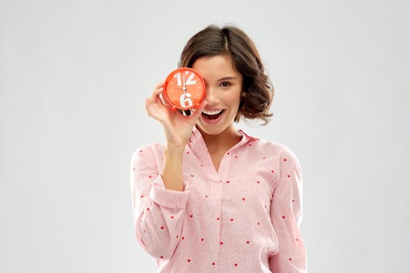 happy young woman in pajama with alarm clock