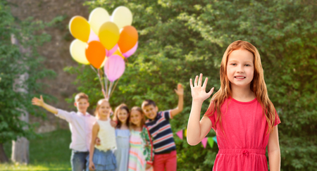 red haired girl waving hand at birthday partyの写真素材