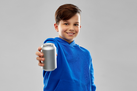 Smiling boy in blue hoodie holding can drinkの写真素材