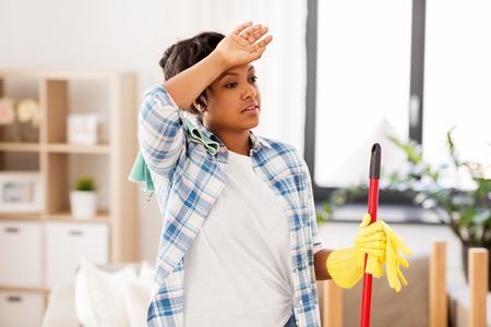 Tired African woman or housewife cleaning at homeの写真素材