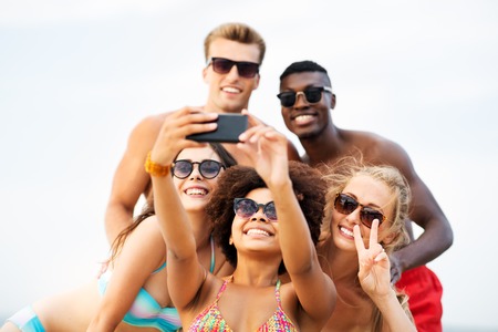 Happy friends taking selfie on summer beach