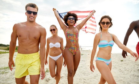 happy friends with american flag on summer beach