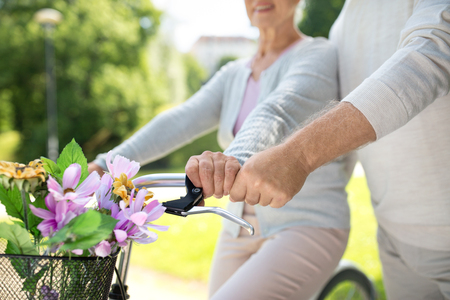 old age, people and lifestyle concept - close up of senior couple with fixie bicycles at summer city parkの写真素材