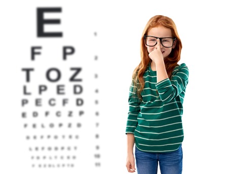 Red haired girl in glasses over eye test chart