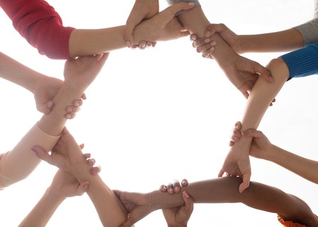 diversity, race, ethnicity and people concept - close up of happy international women holding to each other handsの写真素材
