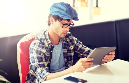 leisure, technology, communication and people concept - creative man with tablet pc computer sitting at cafe tableの写真素材