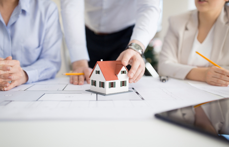 architecture, construction business and people concept - close up of architects with blueprint discussing house project at officeの写真素材