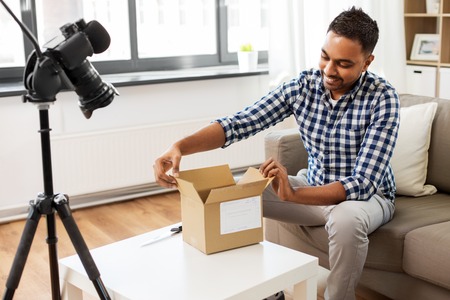 male video blogger opening parcel box at home