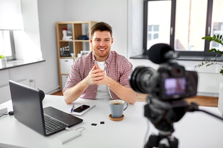 Male blogger with camera video blogging at home