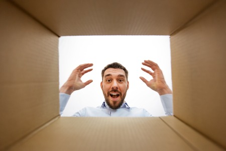 Happy surprised man looking into open parcel boxの写真素材