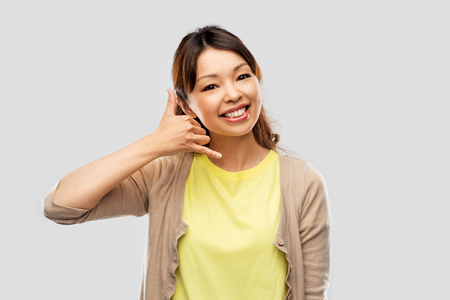 Beautiful Asian making phone call gestureの写真素材