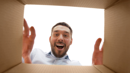 smiling man taking something out of parcel boxの写真素材