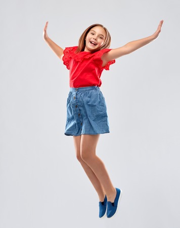 happy smiling girl in red shirt and skirt jumpingの写真素材