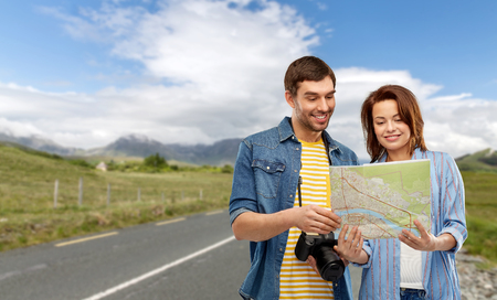 happy couple of tourists with map and cameraの写真素材