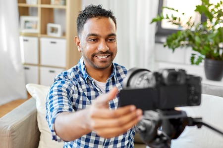 indian male video blogger adjusting camera at homeの写真素材