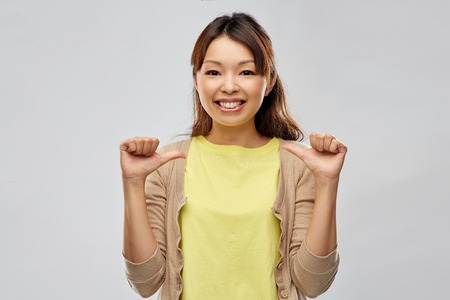 happy asian woman pointing thumbs to herselfの写真素材