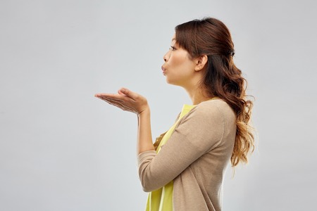 asian woman holding something on hand and blowingの写真素材