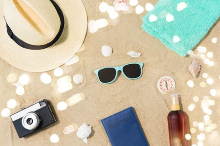 camera, passport, sunglasses and hat on beach sandの写真素材