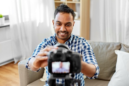 indian male video blogger adjusting camera at homeの写真素材