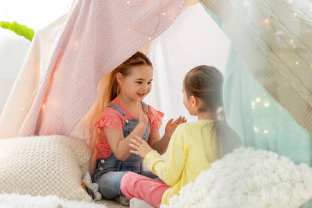 girls playing clapping game in kids tent at homeの写真素材