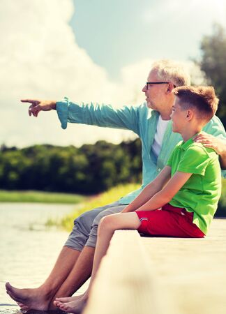 grandfather and grandson sitting on river berthの写真素材