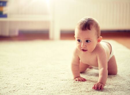 little baby in diaper crawling on floor at homeの写真素材